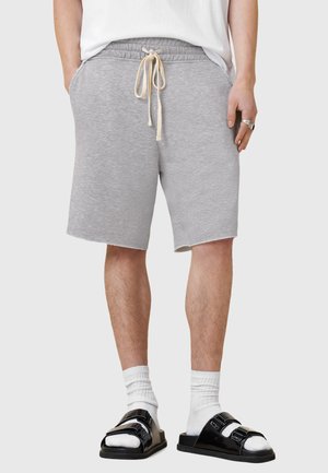 Grå bomuldsblandingsshorts med elastisk talje, snøre og sidelommer; bæres med sorte sandle og hvide crew-sokker.