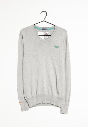 Pull gris clair à manches longues et col en V avec petit logo bleu sarcelle sur la poitrine, suspendu sur un cintre noir sur fond blanc.
