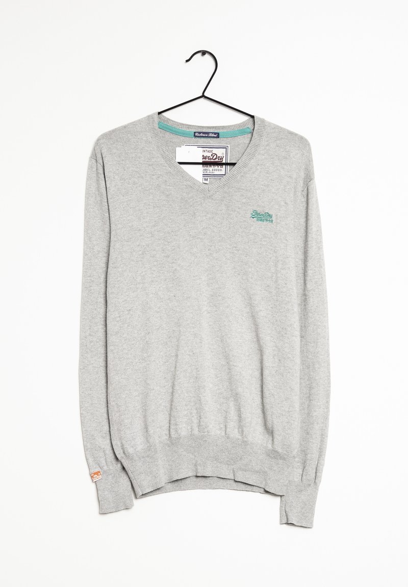 Pull gris clair à manches longues et col en V avec petit logo bleu sarcelle sur la poitrine, suspendu sur un cintre noir sur fond blanc.