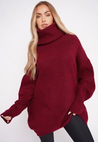 Bordowy, oversize sweter z wysokim kołnierzem, prążkowaną teksturą i długimi rękawami, o luźnym kroju i opadającej sylwetce.