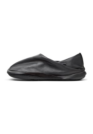 Scarpa nera in pelle, slip-on, con una texture morbida e stropicciata e profilo basso. Presenta una suola flessibile e un design minimalista senza parti metalliche visibili.