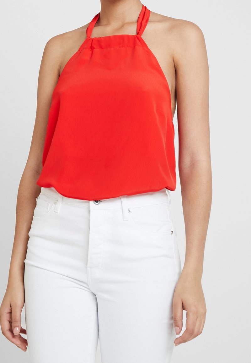Rode mouwloze haltertop van lichtgewicht stof met een zachte textuur, gecombineerd met hoge taille witte jeans.