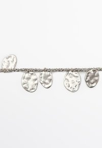 Silverfärgad armband med en vriden kedja och fem oregelbundna, hamrade metallovalformade hängen som hänger jämnt fördelade mot en vit bakgrund.