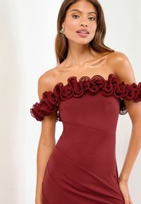 Burgundy off-shoulder mekko, jossa on kerrokselliset rypytysaksentit kaula-aukossa, sileä istuva siluetti ja kulmatikkaukset.
