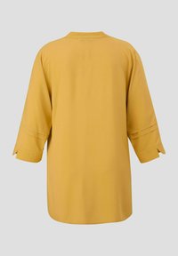 Gelbes, locker sitzendes Hemd mit Dreiviertelärmeln, rundem Halsausschnitt und geradem Saum. Glatter Stoff mit minimalen Details.