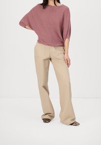 Löysä ribbineulottu viininpunainen neule, beiget leveälahkeiset housut ja leopardi-kuosiset kengät. Pehmeä kangas ja rento siluetti.