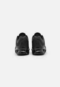 Pantofi sport negri cu un superior texturat, tocuri rotunjite și talpa lucioasă. Designul prezintă contururi dinamice și secțiuni din plasă respirabilă.