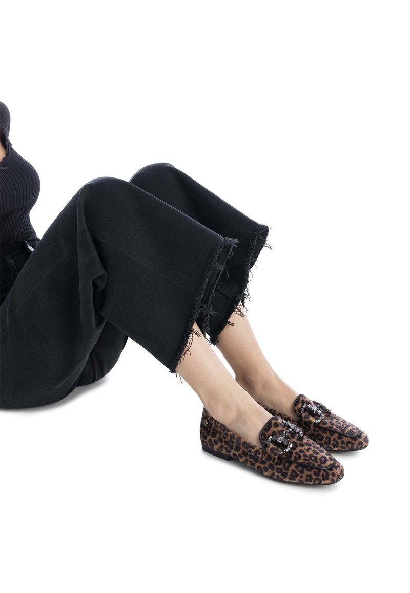 Mocasines con estampado de leopardo, con punta redondeada y detalle decorativo de hebilla. Textura suave con suelas planas. Combinados con pantalones anchos negros deshilachados.