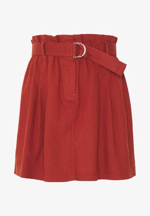 Falda de algodón roja con diseño plisado, cintura alta con cinturón y hebilla de anillo en D plateada, y bolsillos en las costuras laterales.