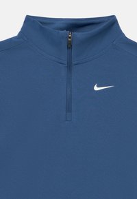 Πουλόβερ με φερμουάρ μέχρι το στήθος σε μπλε ύφασμα, με ψηλό γιακά, λεία υφή και λευκό λογότυπο Nike στο πάνω αριστερό μέρος.