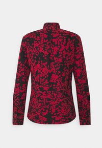 Zwart shirt met een rood bloemenpatroon, lange mouwen en een opstaande kraag. Heeft een gebogenzoom en knoopmanchetten.