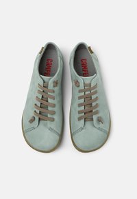 Scarpe in suede verde chiaro con lacci marroni, punta rotonda e suola in gomma. Presentano una soletta testurizzata con il marchio rosso "Camper".