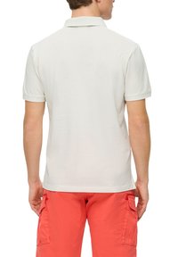 Klassisches Poloshirt in hellem Beige mit Kragen und kurzen Ärmeln, aus weicher Baumwolle mit glatter Textur gefertigt.