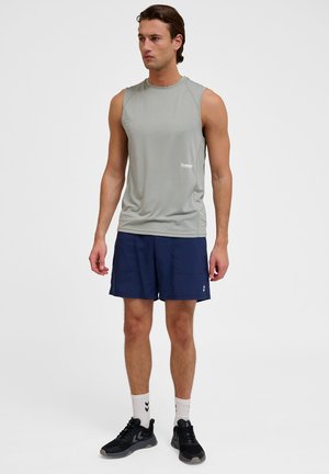 Lysegrå ærmeløs træningsbluse med en tætsiddende pasform, ledsaget af mørkeblå shorts. Outfittet har et diskret logo og mesh-struktur.