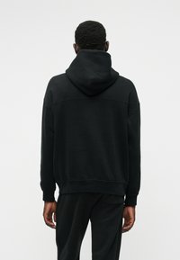 Must have pehmeast kangast must kapuuts, kangaroo tasku, soonikkoesed ja voodriga kapuuts. Disain on lõdvestunud ja ülekaalus.