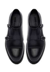 Black leather shoes with two buckle accents, rounded toe, flat sole, and sleek upper design. Smooth texture with subtle shine.