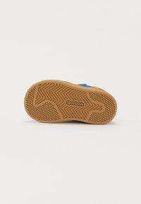 Suela de zapatilla de material de caucho, con un patrón texturizado y el logo de Reebok. Colores dominantes: marrón y acentos azules.