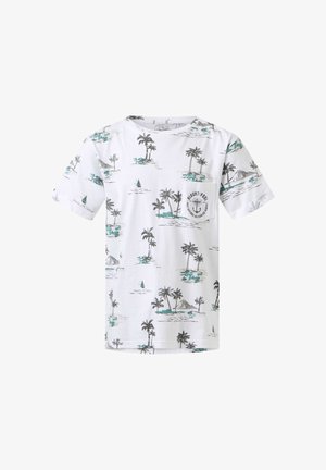 Dreng stående med hånden på nakken, iført hvid t-shirt med palmebladprint, blå jeans og hvide sneakers med grønne striber.