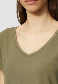 Olijfgroene V-hals t-shirt gemaakt van zachte, lichte stof. Beschikt over korte mouwen en een relaxed fit voor comfort.