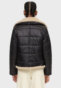 Giacca a vento nera con design trapuntato, collo in falso shearling e orlo elastico. Presenta una lunghezza corta e tessuto texturizzato.