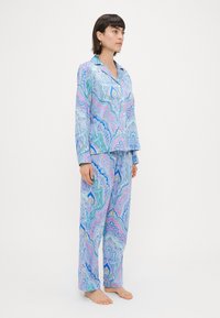 Set de pijama cu imprimeu albastru, având mâneci lungi și pantaloni largi. Materialul prezintă modele complexe paisley în nuanțe de albastru, roz și galben.