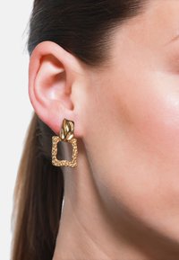 Goldene Ohrringe mit einem strukturierten, gehämmerten quadratischen Design und einer gewölbten oberen Akzentuierung. Die Oberfläche ist spiegelnd und komplex.