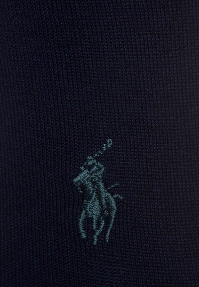 Tamsiai mėlynas megztas audinys su išsiuvinėtu žalsvai mėlynu polo žaidėjo logotipu, demonstruojantis glotnią tekstūrą ir klasikinį dizaino elementą.