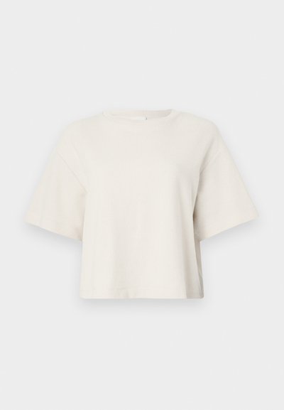 Tricou scurt de culoare crem, realizat din material cu nervuri, având un guler rotund și mâneci scurte, cu o croială lejeră.