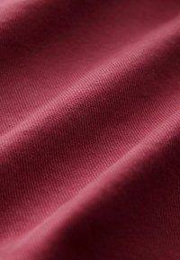 Textilie v hluboké burgundy barvě, s hladkým, mírně texturovaným povrchem a výraznými diagonálními tkaninovými vzory.