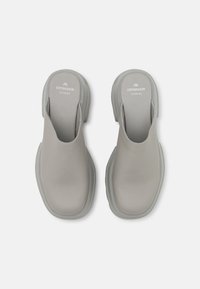 Lichtgrijze leren instapschoenen met een ronde neus, open achterkant en gestructureerde zool. Beschikt over merknaam op de binnenzolen. Glad oppervlak.