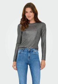 Metaalgrijs langemouwen shirt met een geribbelde textuur, ronde halslijn en aansluitend ontwerp, gecombineerd met lichtblauwe high-waisted jeans.
