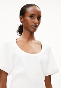 Weißes T-Shirt mit kurzen Ärmeln und rundem Ausschnitt, aus geripptem Stoff, mit lockerer Passform und glatter Textur. Minimalistisches Design.