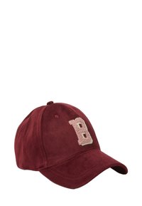 Cappello da baseball in velluto a coste color marrone scuro con un emblema "B" morbido e testurizzato di colore rosa chiaro sul davanti. Presenta una visiera curva e una fascia posteriore regolabile.