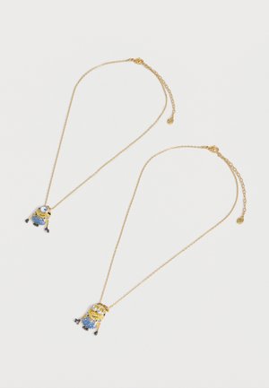 Deux chaînes en or avec des pendentifs en forme de Minion ornés de cristaux bleus et dorés, posées à plat sur un fond blanc.