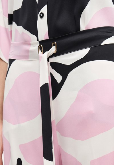 Blomstertryckt tyg med rosa, svart och krämfärgade nyanser. Har ett midjebälte med guldfärgade detaljer, slät textur och knappstängning.