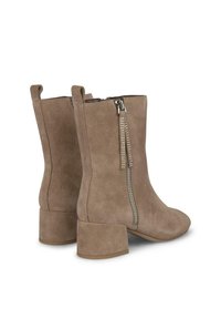 Botas de tobillo de ante color beige con tacón cuadrado, que cuentan con un zipper lateral con remaches decorativos y una textura suave.