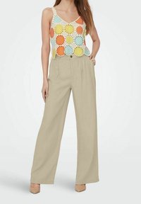 Top de ganchillo con patrones circulares coloridos en naranja, azul y amarillo; combinado con pantalones sueltos de talle alto en beige.