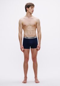 Bóxers de color azul marino con una cintura plateada que presenta el texto "KARL LAGERFELD" en negro. Tela suave y silueta ajustada.