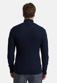 Marineblauer Strickpullover mit vertikalen Rippen, hohem Kragen und taillierten Ärmeln, gefertigt aus strukturiertem Stoff.