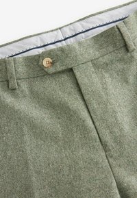 Grüne strukturierte Hose mit einem einzigen Knopfverschluss, flacher Vorderseite und kontrastierender Innenauskleidung. Aus glattem Material mit tailliertem Schnitt.