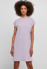 Robe lavande à manches courtes en tissu doux. Elle présente un col rond et une coupe décontractée, arrivant au milieu de la cuisse avec un minimum de détails.