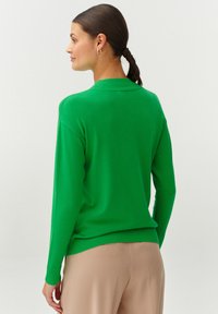 Groene pullover trui met een ronde halslijn, lange mouwen, ribbelmanchetten en een ribbelzoom. Gemaakt van gladde, elastische stof.