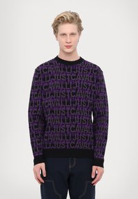 Purple and black patterned sweater featuring a repeated text design, round neckline, and ribbed cuffs and hem. Cotton material.