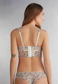 Bloemenkant bralette en bijpassende string. Bevat pastel bloemenpatronen, verstelbare bandjes en delicate kantafwerkingen langs de randen.