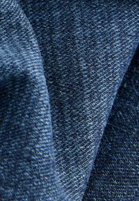 Tela de denim en azul oscuro, con una textura suave y un sutil brillo. El tejido presenta diferentes tonalidades de azul y un fino detalle.