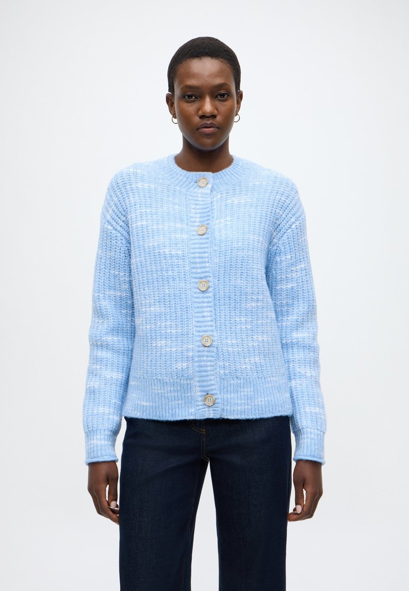 Γαλάζια πλεκτή ζακέτα με ριμπ υφή, στρογγυλή λαιμόκοψη και πέντε μεγάλα κουμπιά κατά μήκος του μπροστινού μέρους. Μακριά μανίκια και άνετη εφαρμογή.