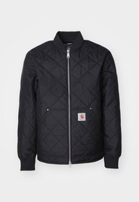 Sort quiltet jakke med frontlynlås, ribkanter og et logopatch. Stoffet er glat med et diamantmønster.