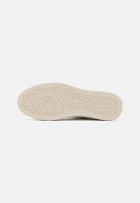Hvit sneakersåle med teksturert fiskebensmønster og sirkulære detaljer; lett gummimateriale; glatt overflate.
