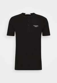 Černá bavlněná krátkozáda halenka henley s tříknoflíkovou légou a bílým logem "Calvin Klein Jeans" na levém prsu.