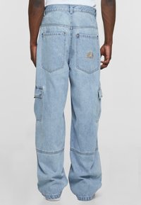 Lyseblå denim cargo bukser med avslappet passform, som har to sidelommer, to baklommer og brodert regnbue detaljer på linningen.